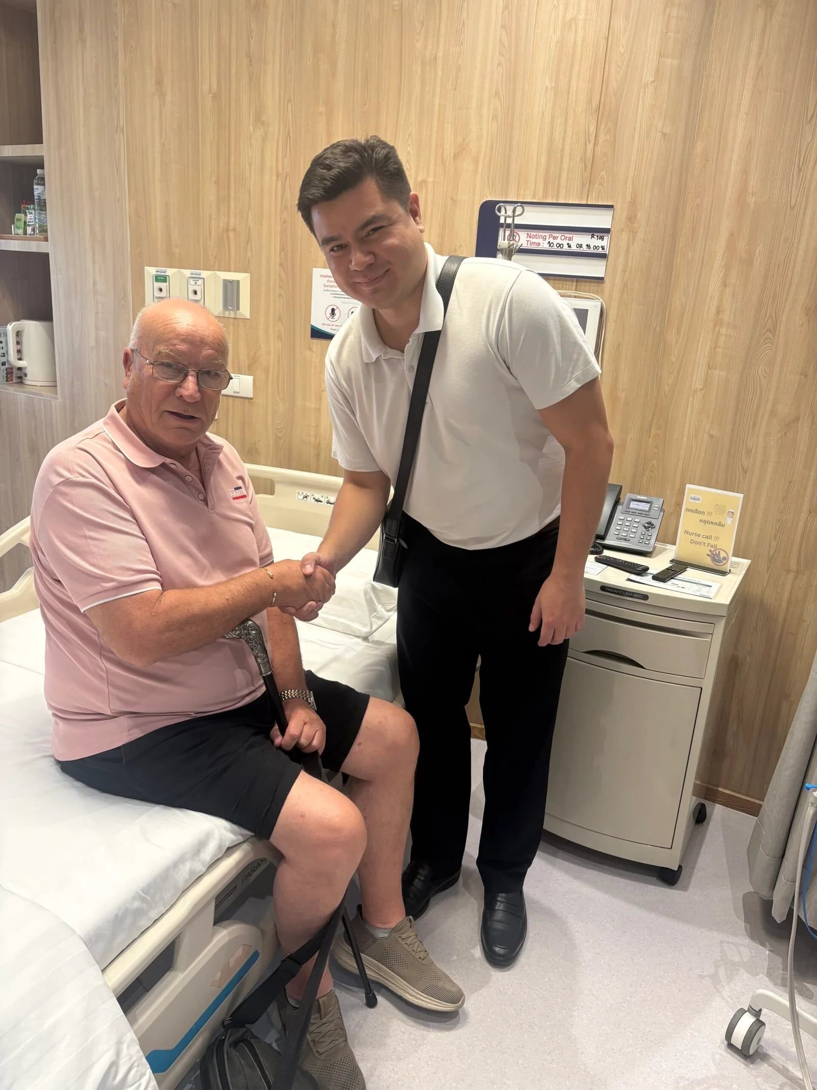 Steven Parker sitting on his hospital bed at KDMS, shaking hands with Alex from Medidash Global